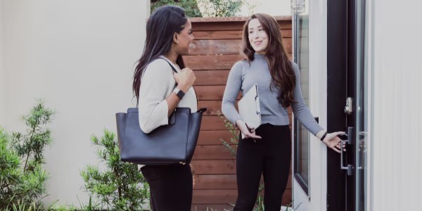 Supra female real estate agent with client at door