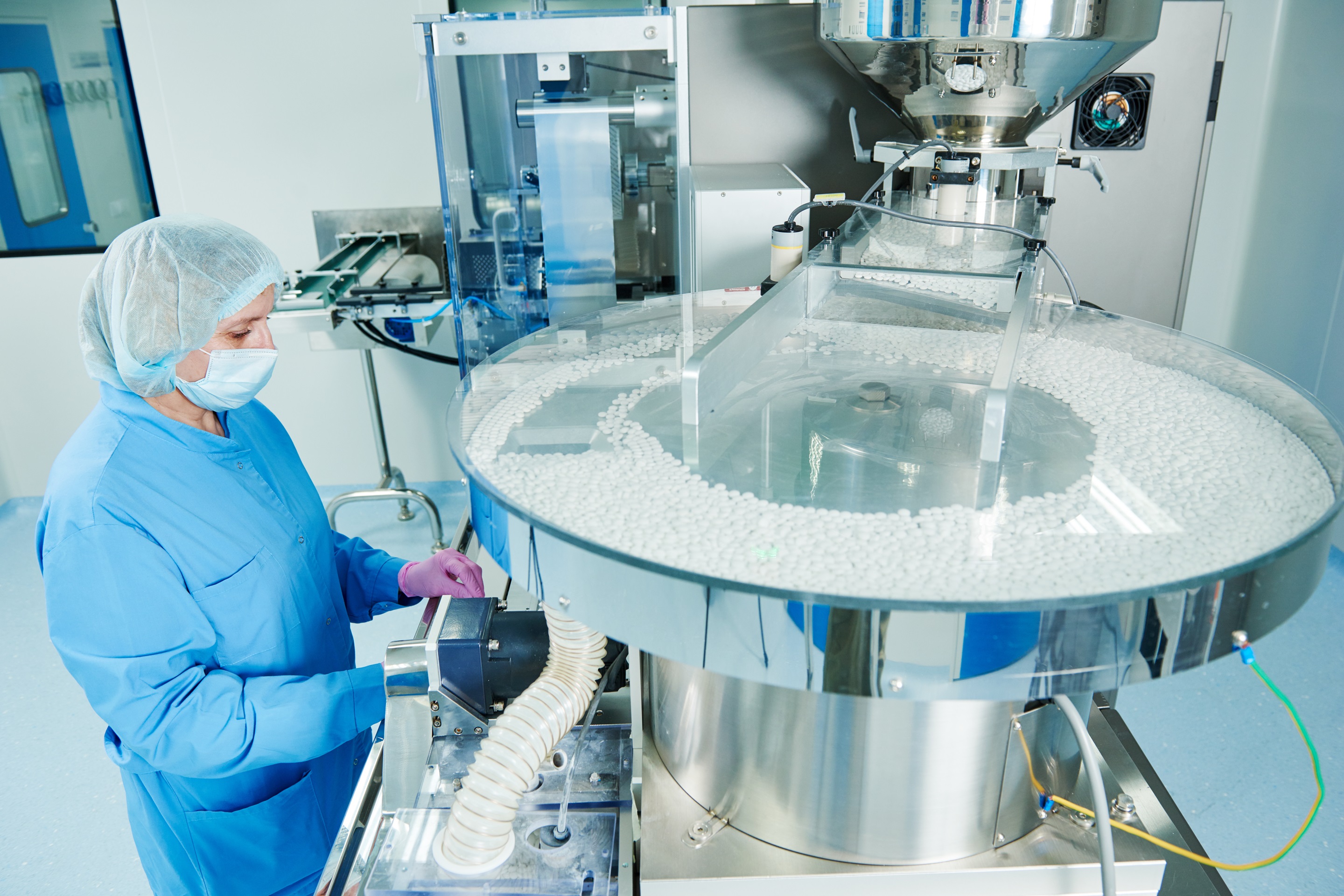 Pharmaceutics. Pharmaceutical industry worker operates tablet blister and cartoning packaging machine at factory